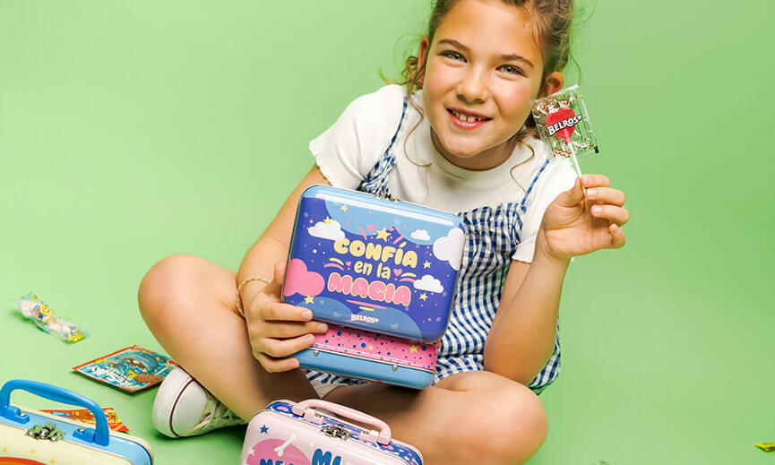 Imagen niña con piruleta Belros y maletas de juguete