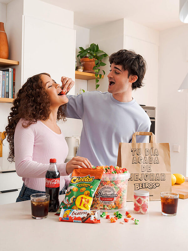 Imagen de una pareja de adolescentes comiendo dulces Belros en una cocina